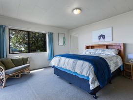 A bedroom with a bed and sofa at Tides and Time Bach - Ahipara Holiday Home, Kaitaia
