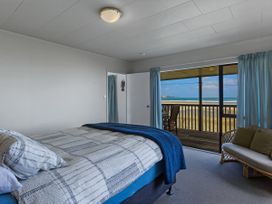 A bedroom with a bed and view of the outdoors at Tides and Time Bach - Ahipara Holiday Home, Kaitaia