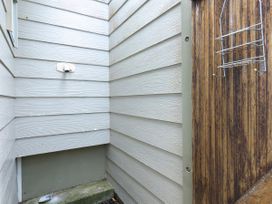 An outdoor area with beige siding and a wooden fence at Tides and Time Bach - Ahipara Holiday Home, Kaitaia