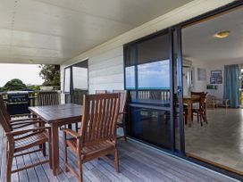A veranda with a table and chairs at Tides and Time Bach - Ahipara Holiday Home, Kaitaia