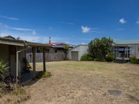 An outdoor area with a grassy space and several houses at Tides and Time Bach - Ahipara Holiday Home, Kaitaia