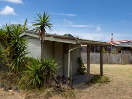 A shed with plants and a fence at Tides and Time Bach - Ahipara Holiday Home, Kaitaia