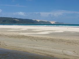 A beach with ocean and sand at Tides and Time Bach - Ahipara Holiday Home Kaitaia