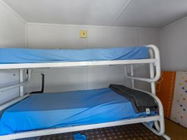 A bunk bed with blue bedding and a blanket at Tides and Time Bach - Ahipara Holiday Home Kaitaia