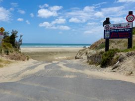 A beach road leading to the ocean at Tides and Time Bach - Ahipara Holiday Home, Kaitaia