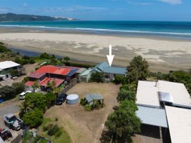 An outdoor view of a house by the beach at Tides and Time Bach - Ahipara Holiday Home Kaitaia