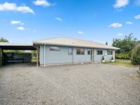 A house with a gravel driveway and garden at Martinborough Holiday Home in Martinborough