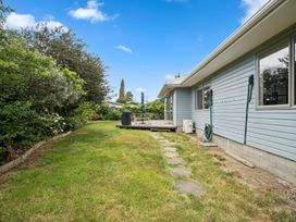 A garden with a deck and grass area at Martinborough Holiday Home in Martinborough