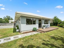 A house with a wooden deck and garden at Martinborough Holiday Home Martinborough