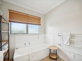 A bathroom featuring a bathtub and shelving at Martinborough Holiday Home in Martinborough