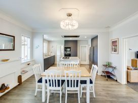 A kitchen with cabinets and a dining table at Deco-licious - Napier Holiday Home, Napier
