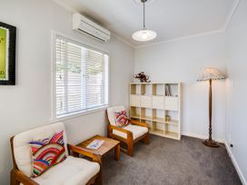 A sitting room with armchairs and a bookshelf at Deco-licious - Napier Holiday Home, Napier