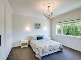 A bedroom with a bed and chandelier at Deco-licious - Napier Holiday Home in Napier
