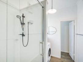 A bathroom with a shower and washing machine at Deco-licious - Napier Holiday Home in Napier