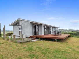 A house with a wooden deck and table at Mania Views Waipu