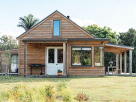 A wooden house with a porch and table at Mangawhai Heads