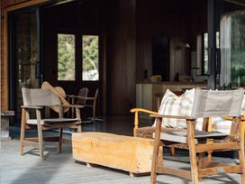 An outdoor area with wooden chairs and bench at Mangawhai Heads