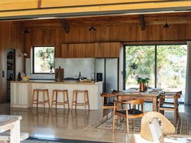 A kitchen with a dining table and stools at Mangawhai Heads