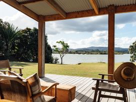 A porch with chairs and a view of water at Mangawhai Heads