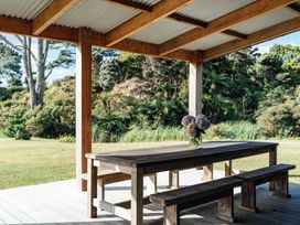 An outdoor dining area with a wooden table and benches at Mangawhai Heads