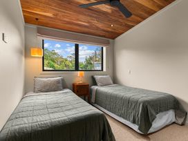 A bedroom with two beds and a window at Mangawhai Heads