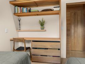 A bedroom with a desk and shelves at Mangawhai Heads