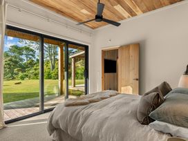 A bedroom with a bed and a sliding door at Mangawhai Heads