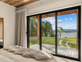 A bedroom with a bed and sliding doors leading to an outdoor view at Mangawhai Heads