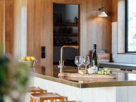 A kitchen with a counter featuring wine glasses and cheese at Mangawhai Heads