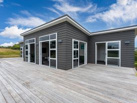 An outdoor view of a modern house with a wooden deck at Motuoapa Holiday Home in Motuoapa