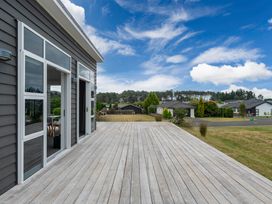 An outdoor area with a wooden deck and view of houses at Motuoapa Holiday Home in Motuoapa