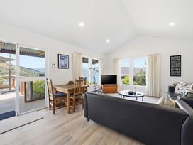 A living room with a dining table and chairs and a television at Harbour Heights - Akaroa