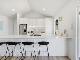 A kitchen with modern appliances and bar stools at Harbour Heights - Akaroa Holiday Home in Akaroa