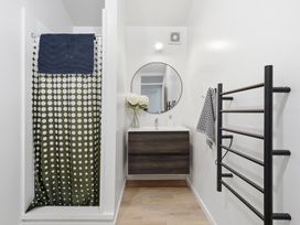 A bathroom with a shower curtain, sink, and towel rack at Harbour Heights - Akaroa Holiday Home, Akaroa