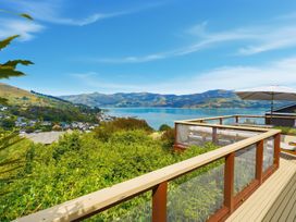 An outdoor area with a deck and view of the water and mountains at Harbour Heights - Akaroa Holiday Home, Akaroa