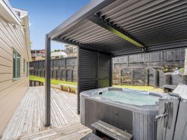 An outdoor area with a hot tub and wooden decking at Petit Paradis - Whitianga Holiday Home Whitianga