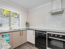 A kitchen with sink and appliances at Petit Paradis - Whitianga Holiday Home