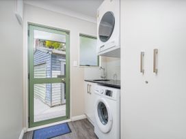 A laundry room with a washing machine and dryer at Petit Paradis - Whitianga Holiday Home, Whitianga