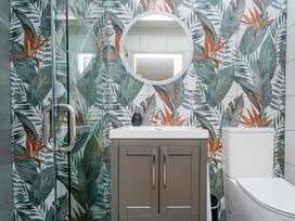 A bathroom featuring a shower, sink, toilet, and mirror at Petit Paradis - Whitianga Holiday Home