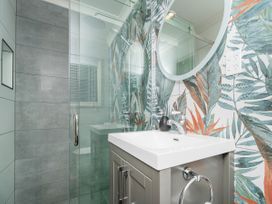 A bathroom with a sink and shower at Petit Paradis - Whitianga Holiday Home
