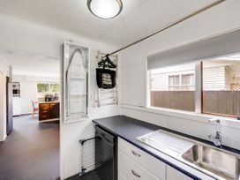 A kitchen with a sink and an ironing board at Napier Holiday Home in Napier