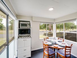 A dining area with a table and kitchen appliances at Napier Holiday Home in Napier