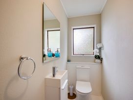 A bathroom with a sink, toilet, and mirror at Napier Holiday Home in Napier