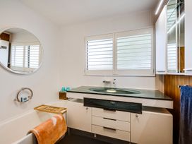 A bathroom with a bath tub and wash basin at Napier Holiday Home in Napier
