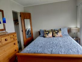 A bedroom with a bed and nightstand at Central Ease - Napier Holiday Home, Napier
