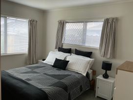 A bedroom with a bed and window at The Orewa Beach House - 200 Steps to Orewa Beach