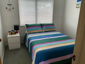A bedroom with a bed and nightstand at The Orewa Beach House - 200 Steps to Orewa Beach in Orewa