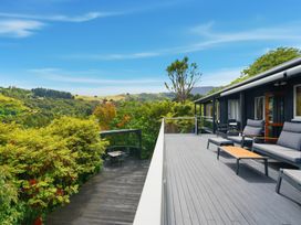 A deck with chairs and a table overlooking greenery at JD'S Place - Akaroa Holiday Home, Akaroa