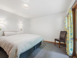 A bedroom with a bed and chair at JD'S Place - Akaroa Holiday Home