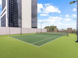 A tennis court with a building in the background at a property in Auckland